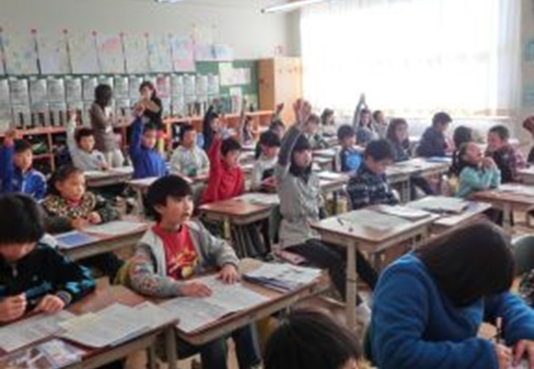 教室で小学生が授業中に挙手している様子